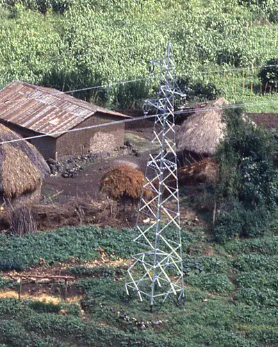 Power lines stretch over a traditional village in a wooded area of Rwanda.