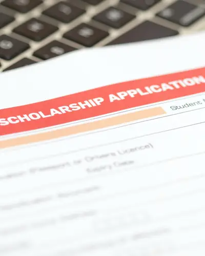 A college scholarship application form, a pen, and a computer keyboard.