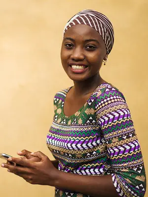 A young African woman reads text messages on a mobile phone.