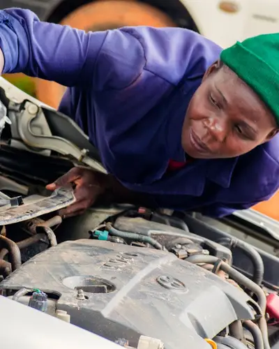 A female mechanic works on a car engine in Bungoma, Kenya.
