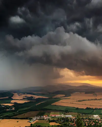 Lightning strikes amid ominous storm clouds above a rural landscape.