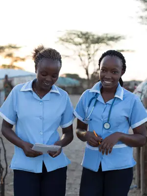 Two African nurses in a village smiling