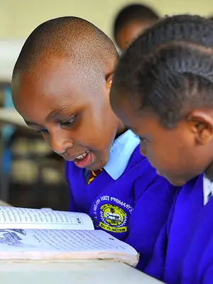 Photo of girl and boy reading textbook together.