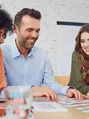 Photo of a group of professionals in a conference room conferring over a table covered in sticky notes.