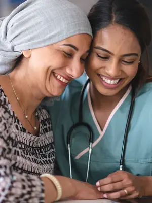 Photo of a patient in a headwrap and a medical practitioner smiling together