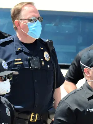 a group of police officers on scene are all wearing protective masks due to the COVID-19 pandemic