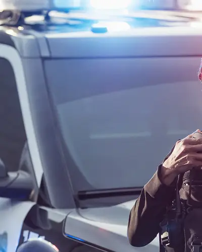 A male and female officer are standing outside a police car talking