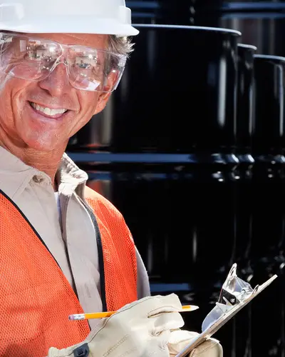 A male worker in a hard hat takes notes in a chemical plant