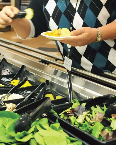 A customer selects food from a salad bar