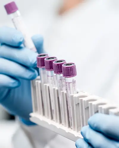 A scientist in a white lab coat works with test tubes.