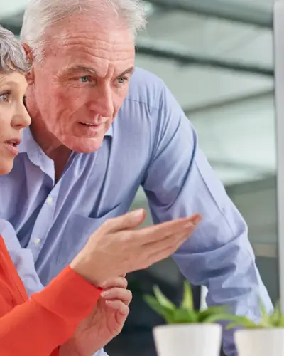 A woman and a man work together on a desktop computer