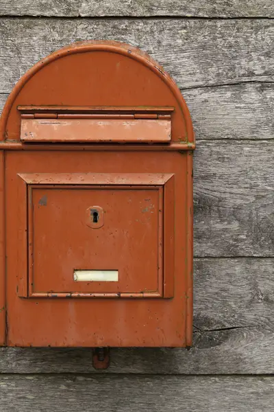 Photo of a red mailbox on a wooden wall.