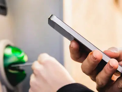 person with mobile phone using atm
