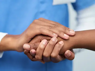 Health care provider holding a patient's hand to provide comfort