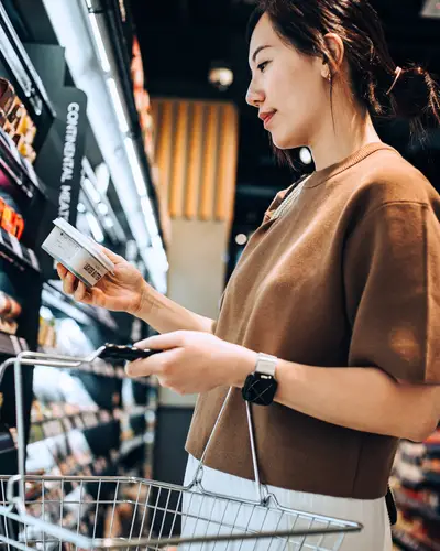 A woman inspects a label while shopping at a grocery store.