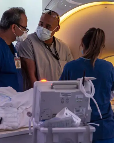 Medical personnel help a patient prepare for an MRI at a military hospital.
