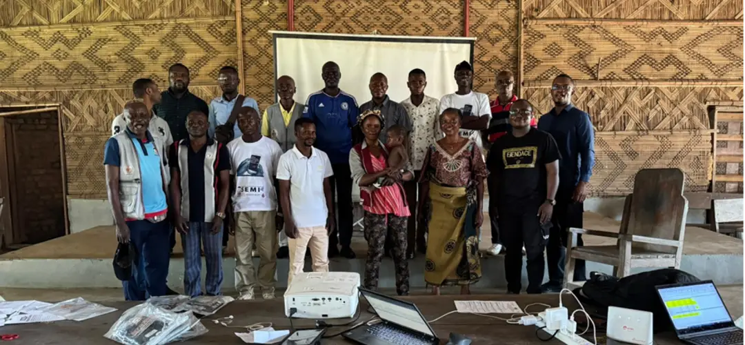 People gathering together for a picture. Majority men with a few women and a baby