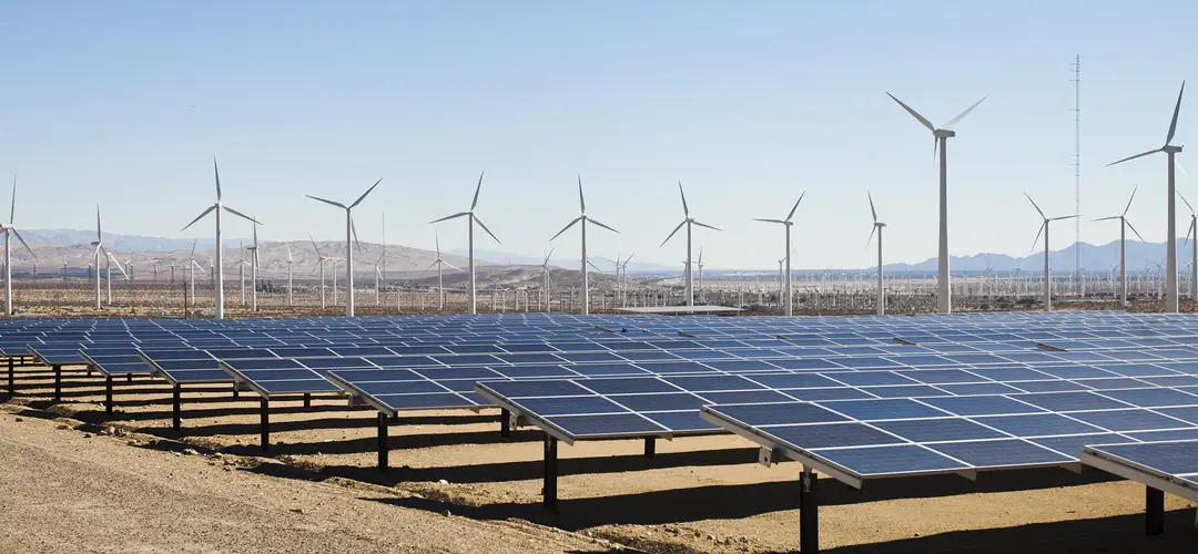 Solar panels with wind turbines in arid renewable energy facility.