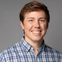 Headshot of Tyler Ovington smiling against a grey background