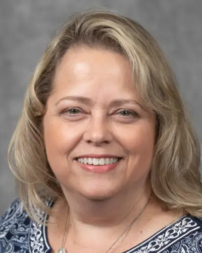 Headshot of Alicia Gilsenan smiling against a gray background