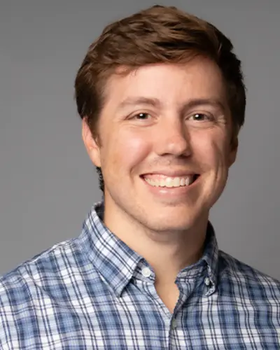 Headshot of Tyler Ovington smiling against a grey background