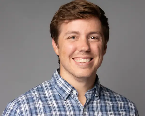 Headshot of Tyler Ovington smiling against a grey background