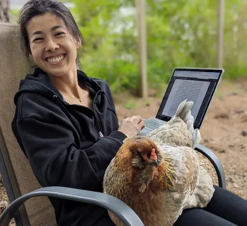 Candise holding her laptop with a chicken on her lap