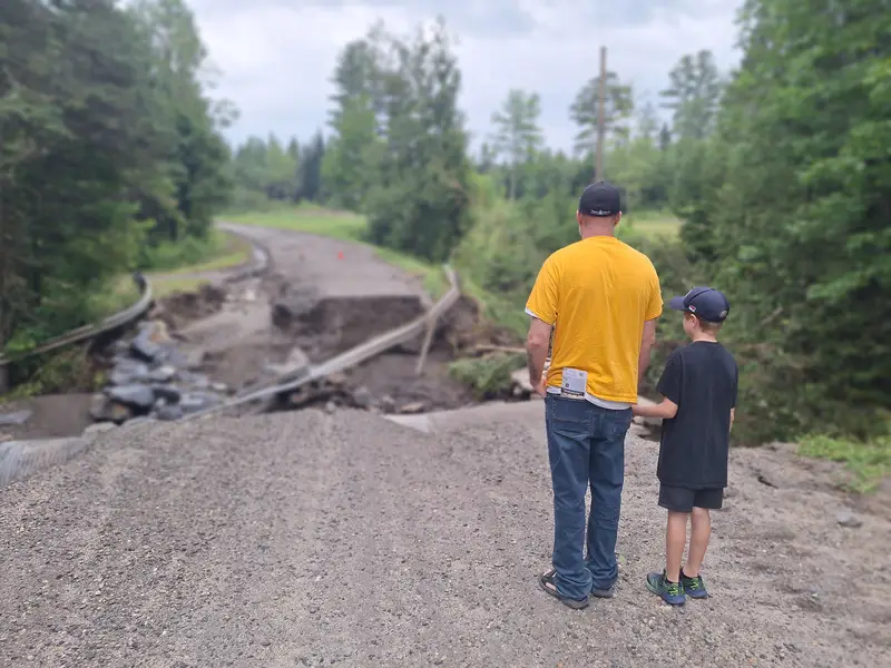Man and boy standing in front of a washed away road