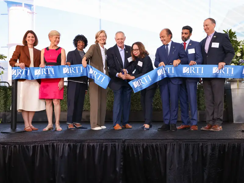 ribbon is cut on stage with large scissors and a group of people is gathered behind the ribbon