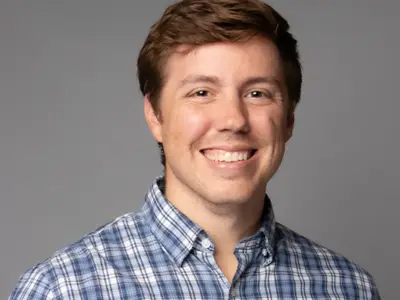 Headshot of Tyler Ovington smiling against a grey background