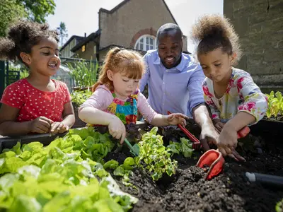 Young children help dig up freshly grown vegetables.