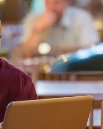 A college student works on a laptop in a university library.