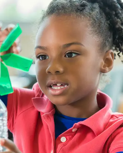 Elementary school-age girl experiments with a windmill