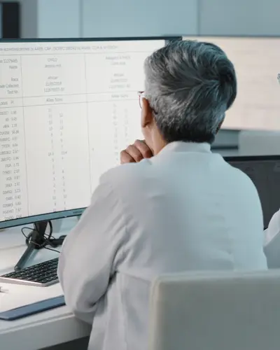 Photo of two scientists in a lab looking at a desktop computer screen