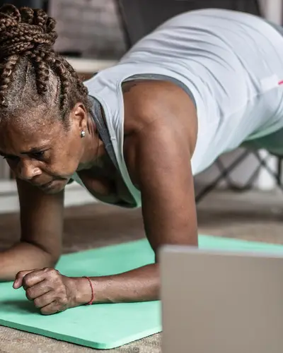 Women exercising on a mat next to her computer