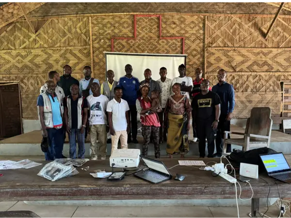 People gathering together for a picture. Majority men with a few women and a baby
