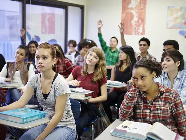 High school students raise their hands to participate in class.