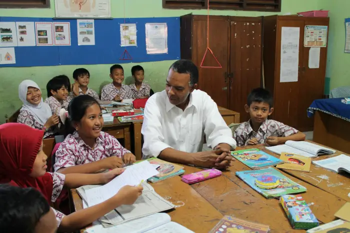 Students engage in discussion with a teacher in a colorful classroom setting.