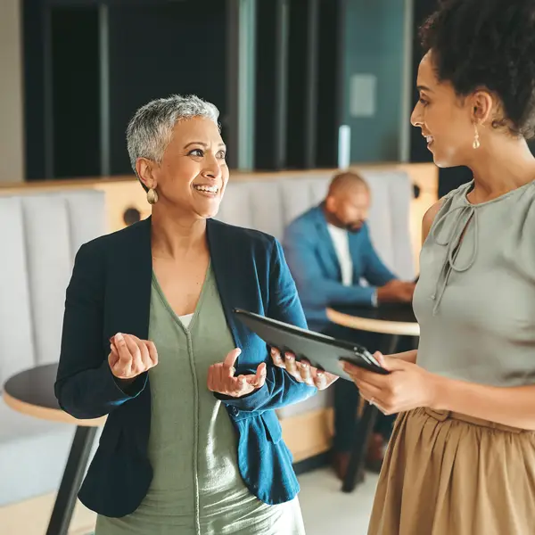 Photo of two women of color talking and smiling in an office