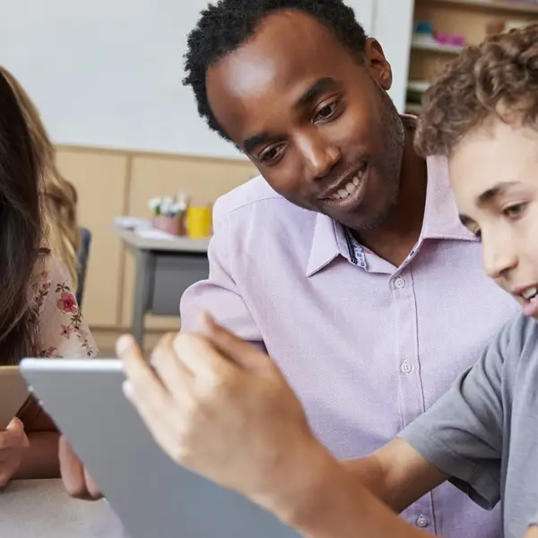 Teacher assisting students with assignments on a tablet