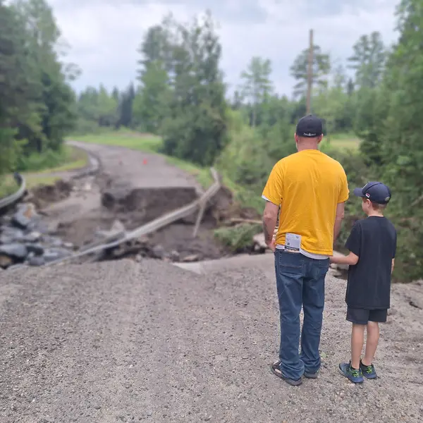 Man and boy standing in front of a washed away road