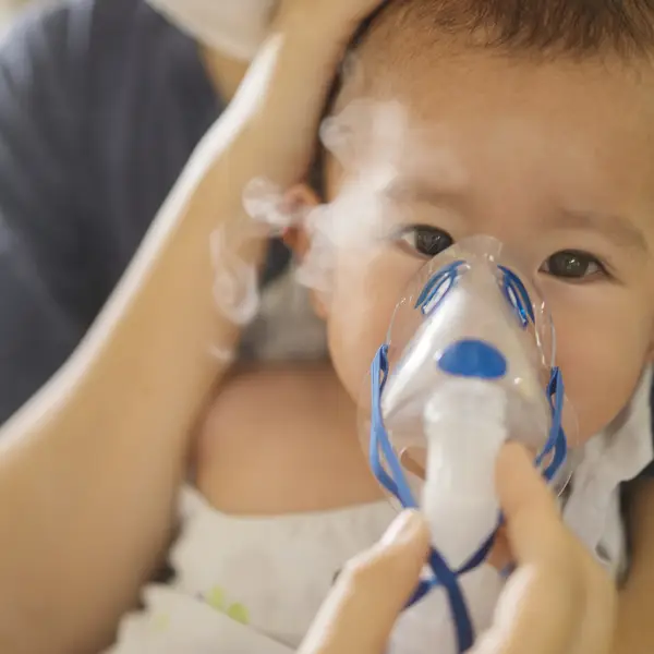Photo of young child using inhaled therapy via a face mask.