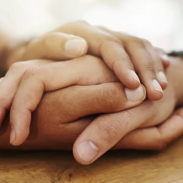 Closeup of two hands touching across a table.