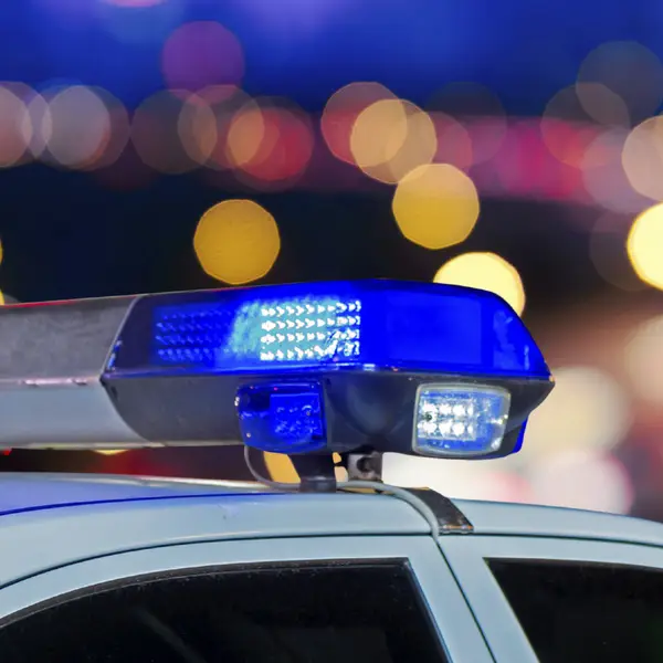 Lights on top of a police car with city lights in the background