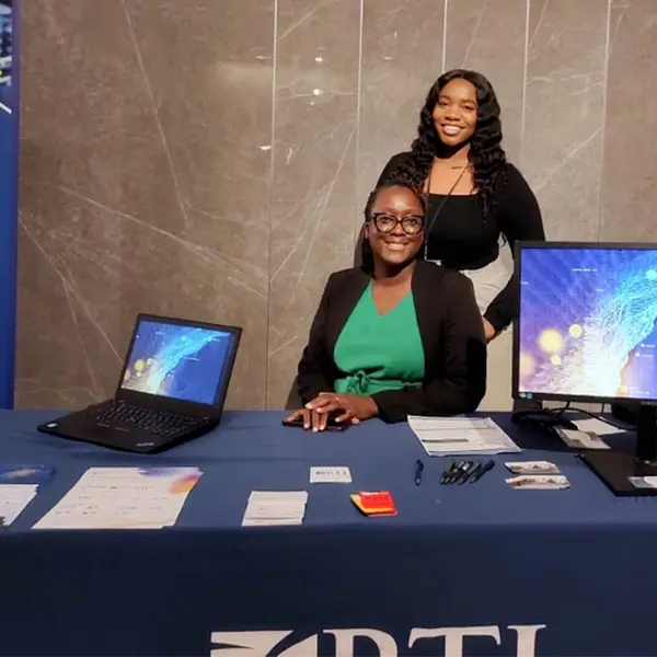 Rita Sembajwe and Shanice Fezeu Meyou pose in front of RTI’s booth at the 2022 DHIS2 Symposium.