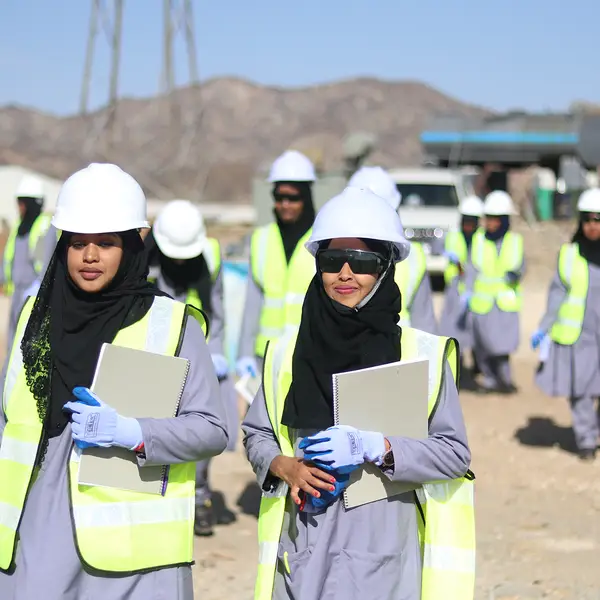 Women in hardhats walk through a solar energy installation during the Somalia GEEL project.