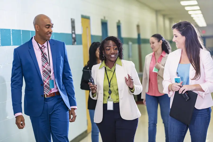 Group of male and female educators walking in school hallway