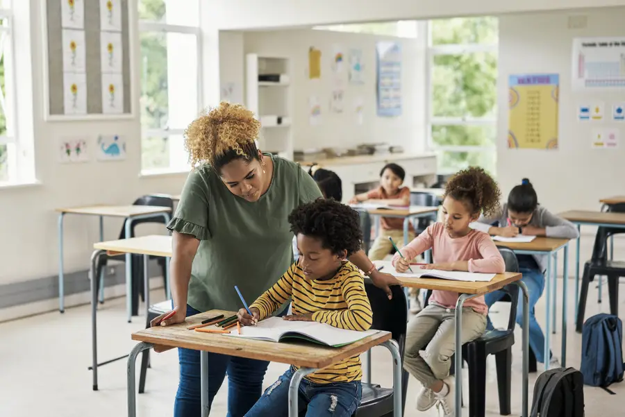 female teacher assisting male student at desk