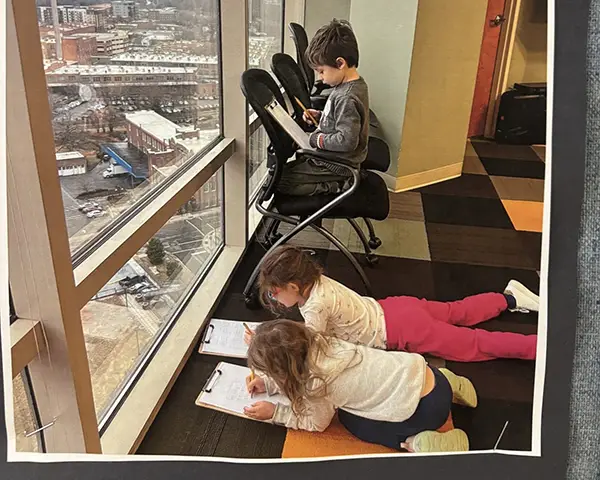 Children looking writing on piece of paper on clipboard