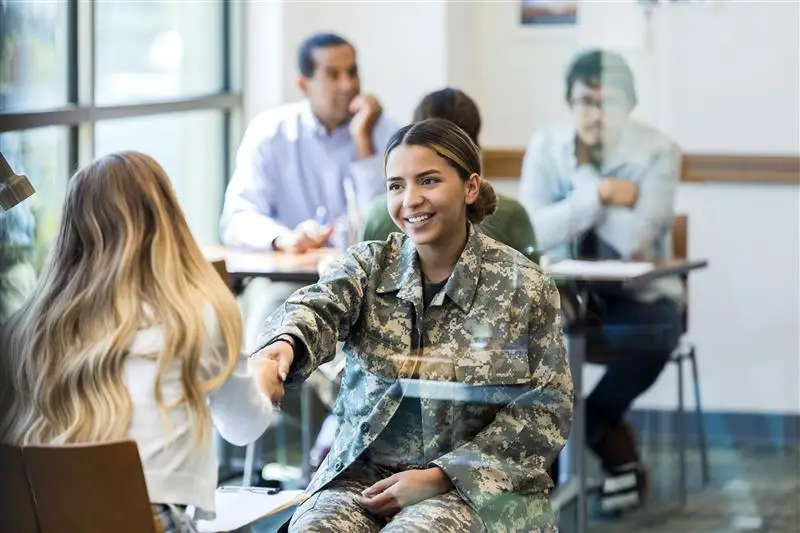 Woman in military uniform shaking another woman's hand